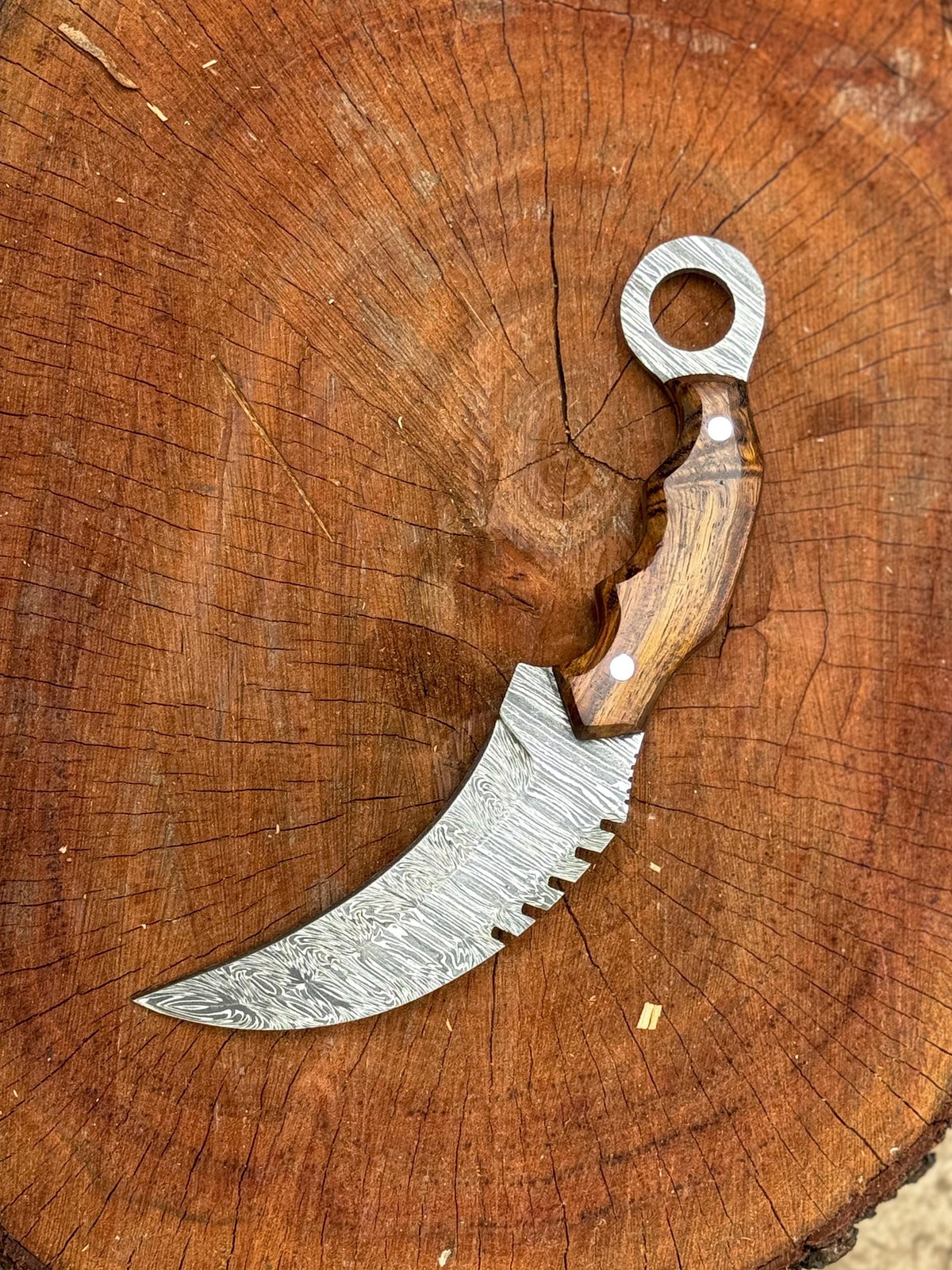 Ergonomic rosewood handle with finger ring grip on Damascus knife

